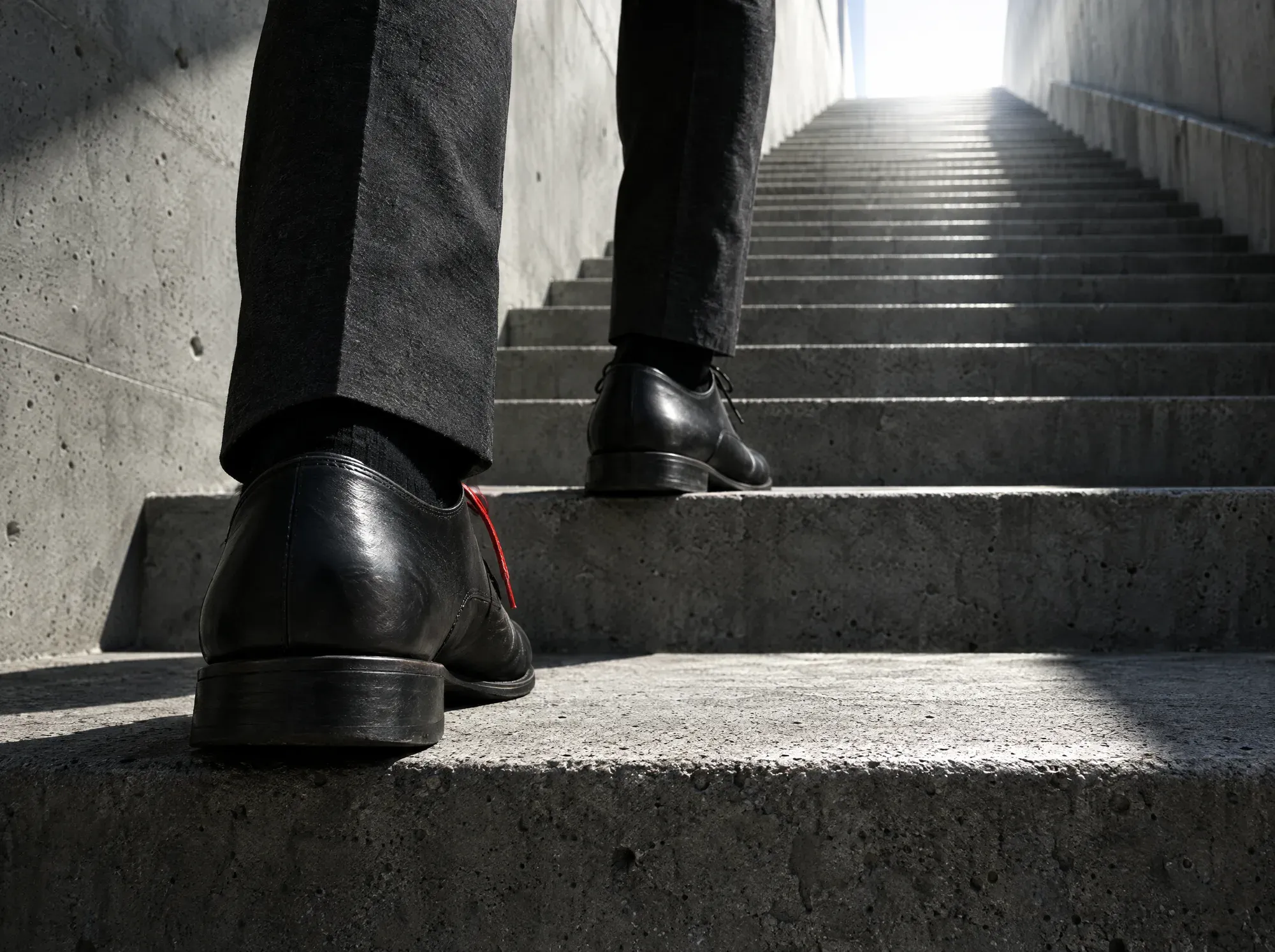 Pied qui se pose sur la première marche d’un escalier en béton.