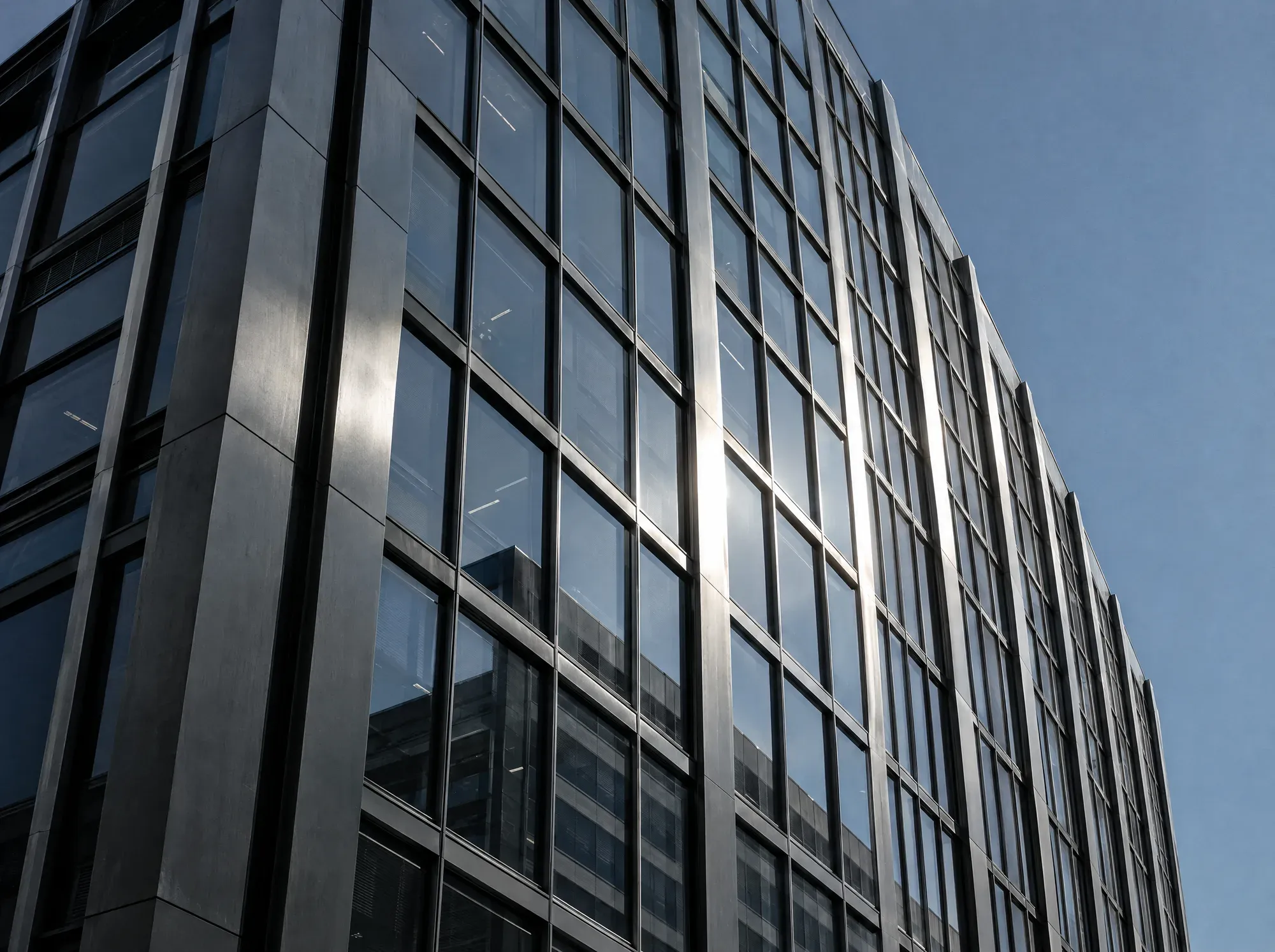 Façade de verre et d’acier vue en contre-plongée, lumière du matin.
