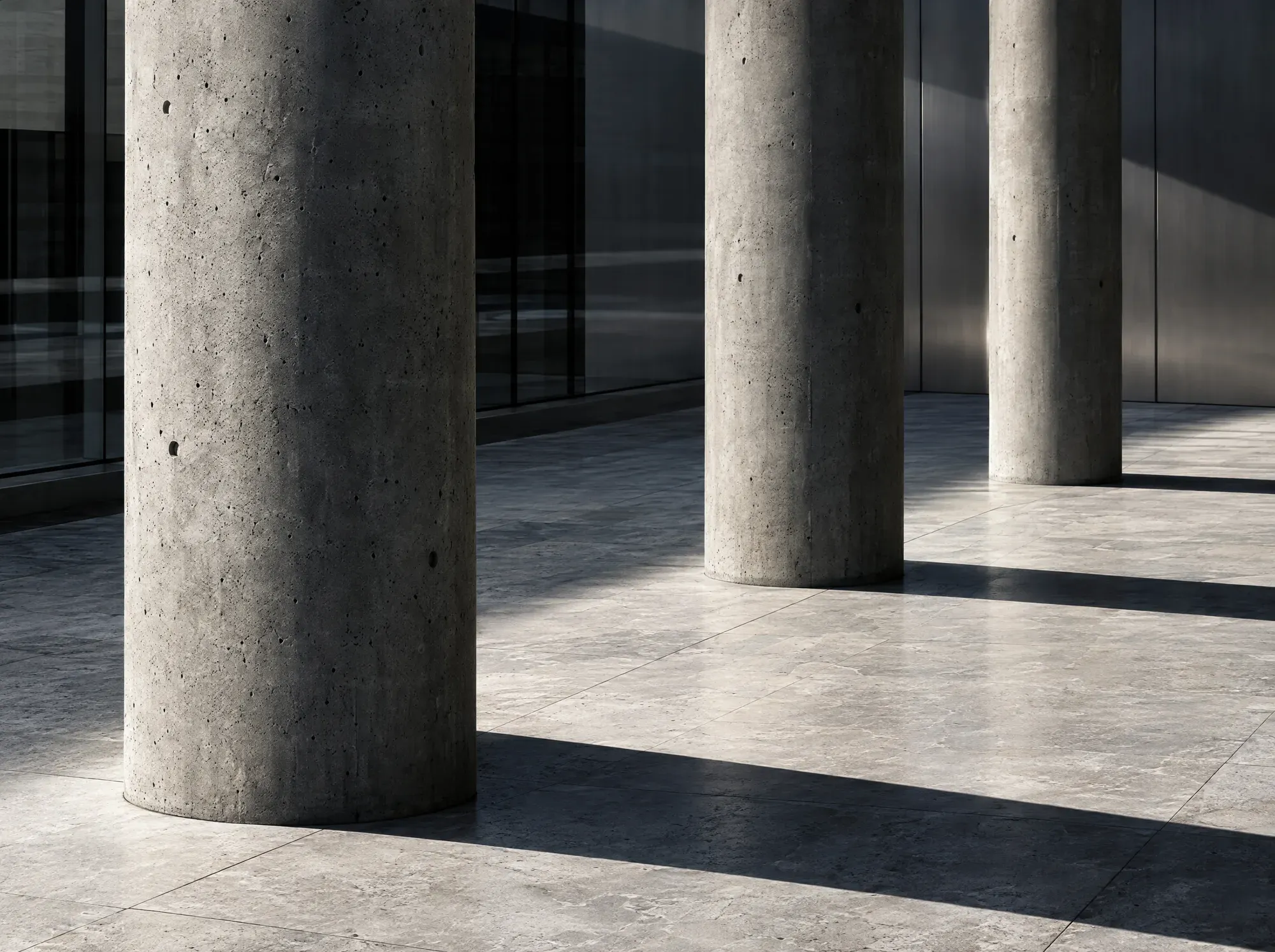 Trois piliers de béton dans une lumière rasante.